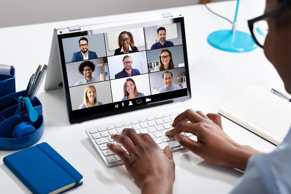 Photo looking over the shoulder of someone on a group Zoom call on a laptop.