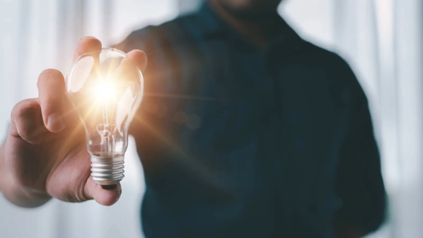 Person holding a bright light bulb.